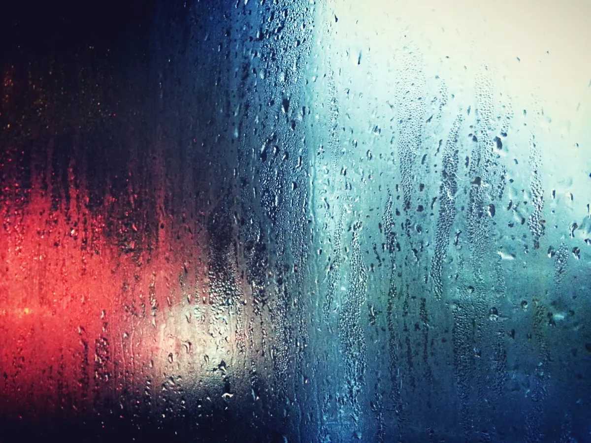 Red and blue light through rain on glass